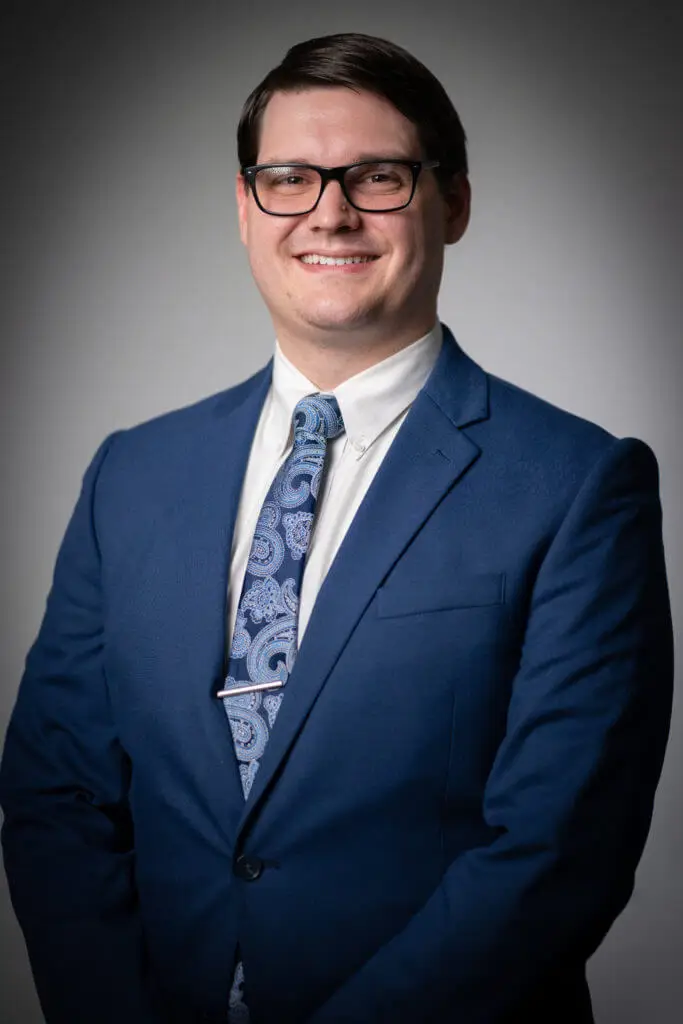 John Hiebel, Financial Controller for EMG Solutions smiles wearing a blue suit